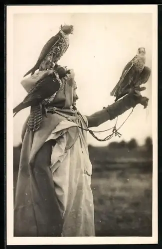 AK Ein arabischer Falkner ist mit seinen beiden Vögeln auf der Jagd