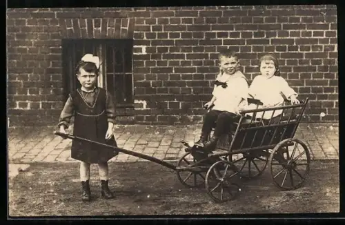 Foto-AK Drei Kinder mit einem Spielzeugkarren