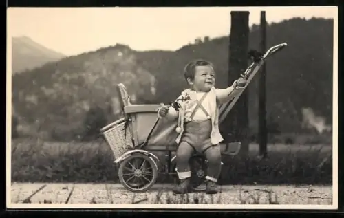 Foto-AK Kind sitzt in einem Kinderwagen im Freien