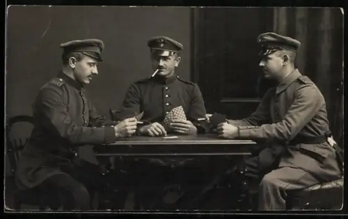 Foto-AK Drei uniformierte Soldaten beim Kartenspiel, einer rauchend