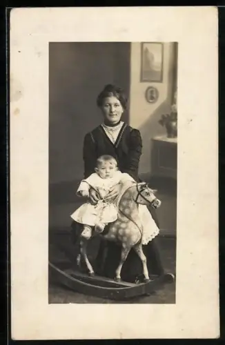 Foto-AK Dame mit Kleinkind, das auf einem Schaukelpferd sitzt