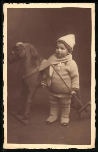 Foto-AK Kind in Winterkleidung mit einem Schaukelpferd