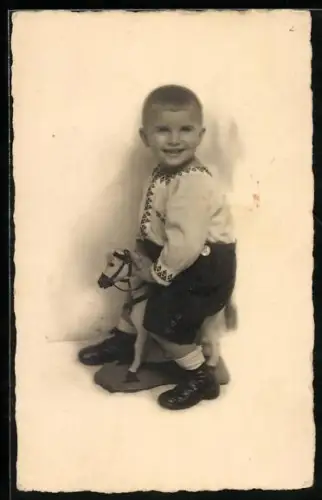 Foto-AK Lächelnder Junge auf einem Spielzeugpferd