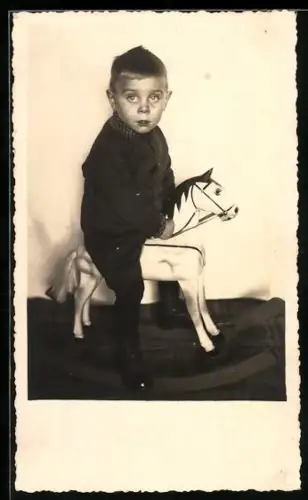 Foto-AK Junge auf einem weissen Schaukelpferd
