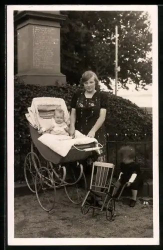 Foto-AK Frau mit Kinderwagen und zwei Kleinkindern an einem Denkmal