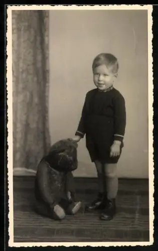 Foto-AK Lächelnder Junge steht neben seinem sitzenden Teddybären