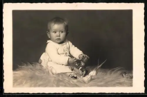 Foto-AK Kleines Kind mit Puppe sitzt auf Fell