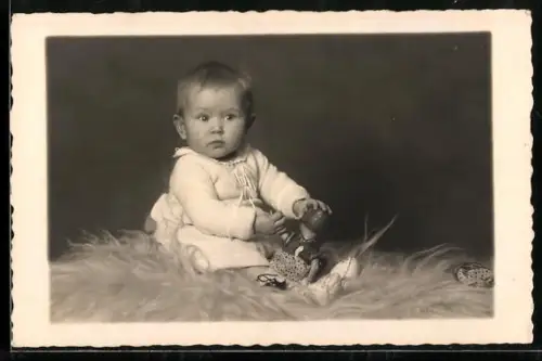 Foto-AK Kleines Kind mit Puppe sitzt auf Fell