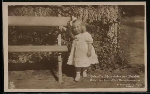 AK Die kleine Prinzessin Alexandrine steht im weissen Kleid mit Schleife im Haar neben einer Bank