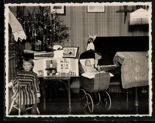 Fotografie kleiens Mädchen an Weihnachten mit Geschenken, Puppenwagen, Kaufmannsladen unterm Weihnachtsbaum