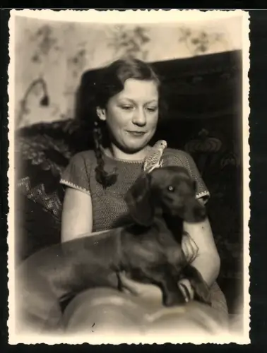 Fotografie junges Mädchen mit ihrem Dackel auf dem Schoss und Wellensittich auf dem Kopf des Hundes