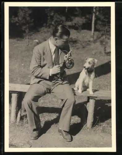 Fotografie junger Mann mit seinem Rauhaar Terrier auf einer Bank