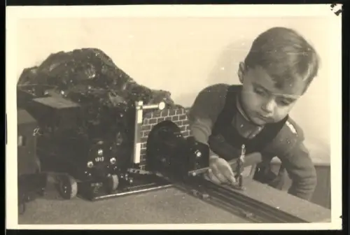 Fotografie junger Knabe spielt mit seiner Holz Eisenbahn