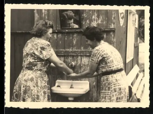 Fotografie zwei Frauen beim Händewaschen, Spiegelung im Spiegel