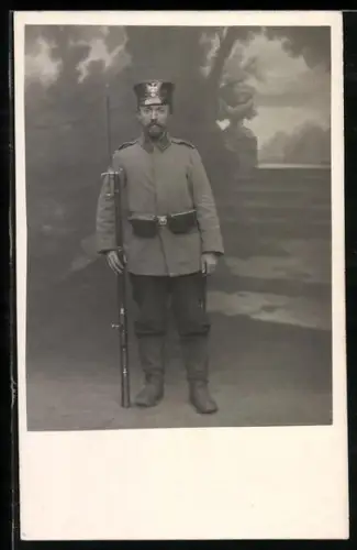 Foto-AK Landwehr-Soldat in Uniform mit Schirmmütze, Koppeltaschen und Gewehr mit aufgepflanztem Bajonett