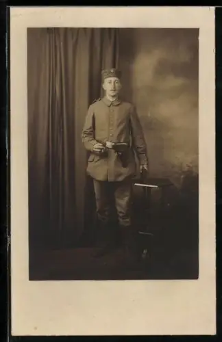 Foto-AK Soldat in Feldgrau Uniform mit Krätzchen und Pistolentasche