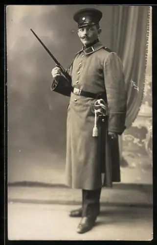 Foto-AK Landwehr-Soldat im Mantel mit Schirmmütze und Gewehr mit aufgepflanztem Bajonett