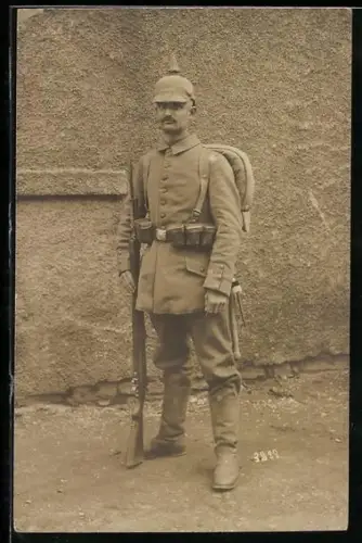 Foto-AK Soldat in Feldgrau Uniform marschmässig ausgerüstet mit Pickelhaube mit Überzug, Ersatz-Bajonett und Gewehr
