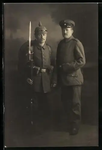 Foto-AK Zwei Soldaten vom Inf.-Rgt. Nr. 75 in Feldgrau Uniformen mit Schirmmütze und Pickelhaube sowie mit Gewehr