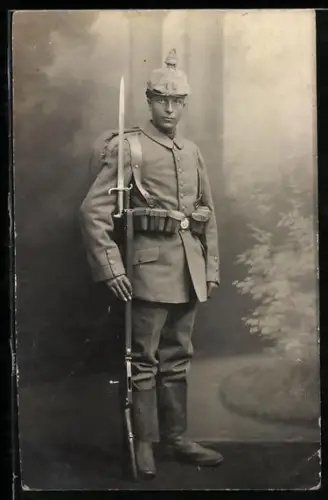 Foto-AK Soldat der Infanterie in Feldgrau Uniform mit Pickelhaube mit Überzug, Patronentaschen und Gewehr