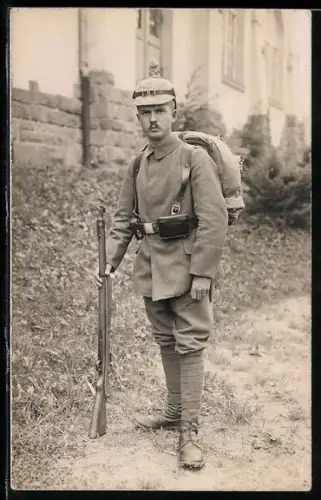 Foto-AK Soldat in Feldgrau Uniform mit Pickelhaube mit Überzug, Tornister, Koppeltaschen und Gewehr