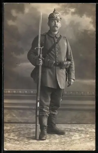 Foto-AK Soldat in Feldgrau Uniform mit Ersatz-Pickelhaube, Patronentaschen und Gewehr 88 mit aufgepflanztem Bajonett 71