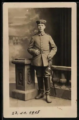 Foto-AK Soldat in Feldgrau Uniform mit Krätzchen und Säbel, 1915