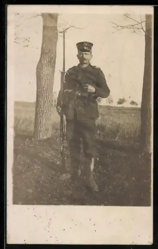 Foto-AK Landwehr-Soldat in Uniform mit Schirmmütze, Patronentaschen, Pfeife und Gewehr mit Bajonett