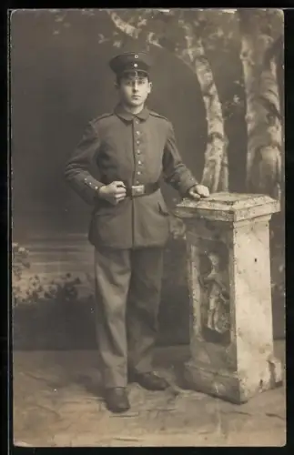 Foto-AK Soldat in Feldgrau Uniform mit Schirmmütze