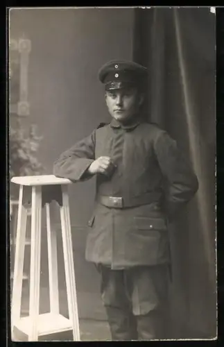 Foto-AK Soldat in Feldgrau Uniform mit Schirmmütze und Bajonett