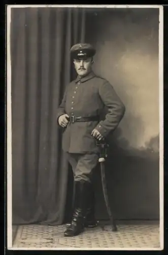 Foto-AK Soldat in Feldgrau Uniform mit Schirmmütze und Säbel, 1916