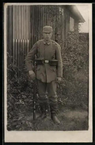 Foto-AK Soldat in Feldgrau Uniform mit Koppeltaschen, Pickelhaube mit Überzug und Gewehr
