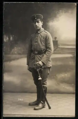 Foto-AK Soldat in Feldgrau Uniform mit Schirmmütze und Säbel