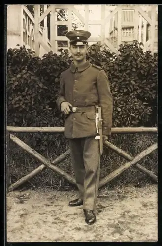 Foto-AK Soldat in Feldgrau Uniform mit Schirmmütze und Ersatz-Bajonett