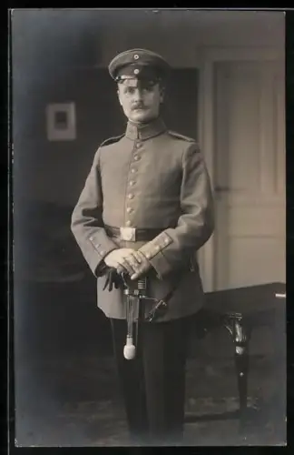 Foto-AK Vizefeldwebel vom Res.-Inf.-Rgt. 40 in Feldgrau Uniform mit Schirmmütze und Säbel