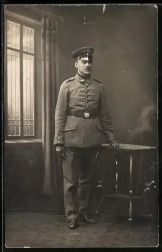 Foto-AK Soldat in Feldgrau Uniform mit Schirmmütze