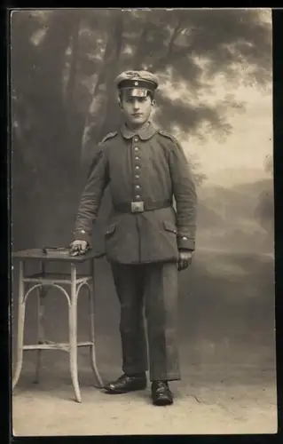 Foto-AK Soldat in Feldgrau Uniform mit Schirmmütze