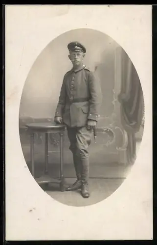 Foto-AK Gefreiter in Feldgrau Uniform mit Schirmmütze und Bajonett