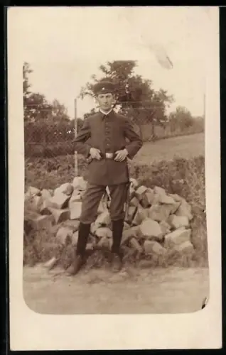 Foto-AK Soldat in Uniform mit Schirmmütze und Feldspaten