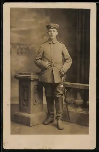 Foto-AK Soldat in Feldgrau Uniform mit Krätzchen und Säbel