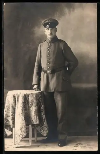 Foto-AK Soldat in Feldgrau Uniform mit Schirmmütze und Band zum EK II 1914