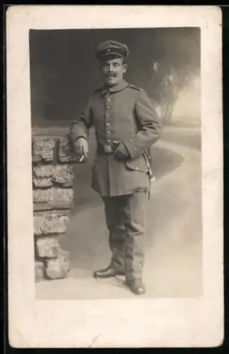 Foto-AK Soldat in Feldgrau Uniform mit Schirmmütze und Bajonett
