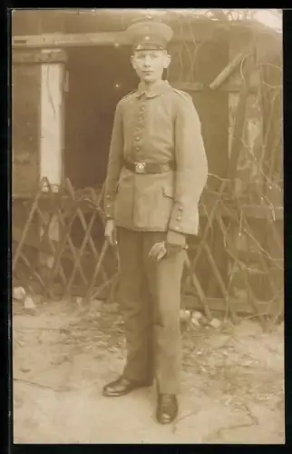 Foto-AK Soldat in Feldgrau Uniform mit Schirmmütze