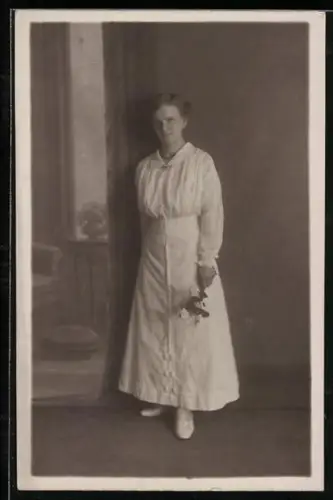 Foto-AK Elegante Dame mit Blumenstrauss vor einer Studiokulisse