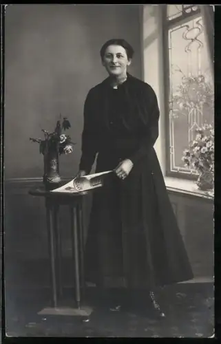 Foto-AK Lächelnde Dame an einem Tisch stehend