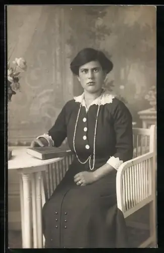 Foto-AK Dame in dunklem Kleid sitzt mit einem Buch am Tisch