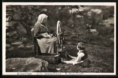 AK Kind betrachtet die Grossmutter bei der Arbeit am Spinnrad