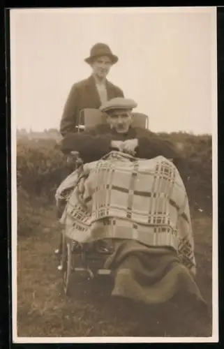 Foto-AK Mann in einem Rollstuhl mit Decke über den Beinen
