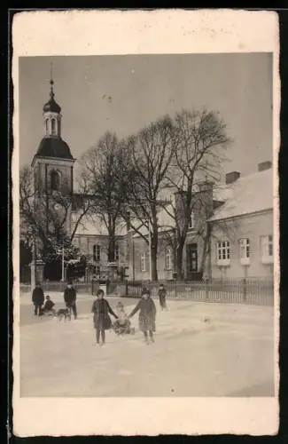 AK Warmsdorf, Kinder mit Schlitten im Schnee vor Kirche