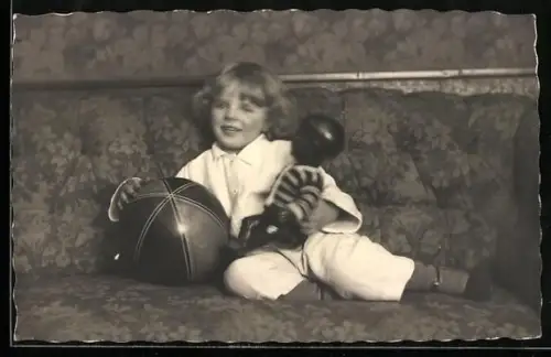 Foto-AK Mädchen sitzt mit Puppe und Ball auf dem Sofa